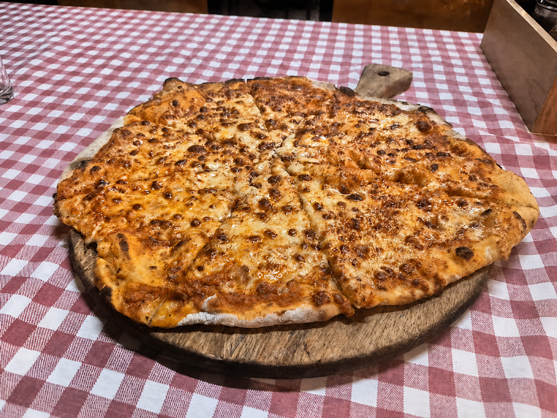 Casa-Mia-Käsepizza auf rot karierter Tischdecke