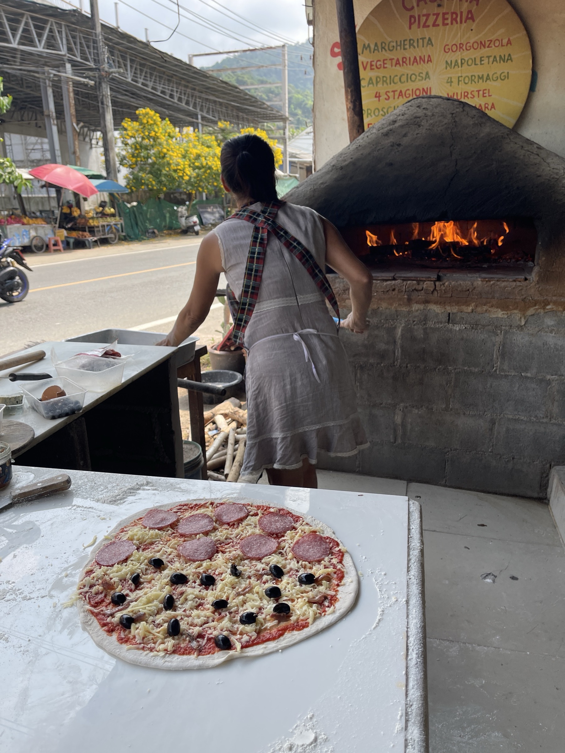 Eine Casa-Mia-Pizza wird neben dem Holzofen zubereitet